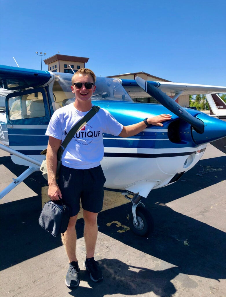 student standing in front of a blue single engine plane