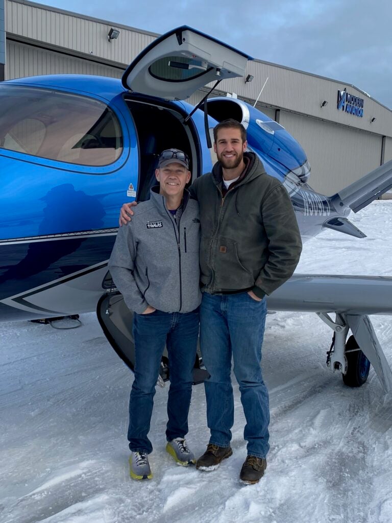 two men standing in front of blue vision jet